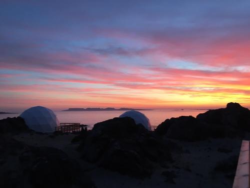 a sunset over the ocean with three domes on the beach at Kunza Kamanchacos in Punta de Choros