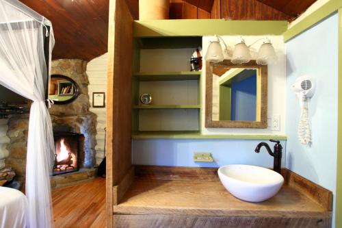 a bathroom with a fireplace and a sink and a mirror at The Pines Cottages in Asheville