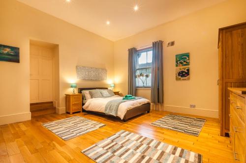 a bedroom with a bed and a window and wooden floors at Elm Lodge in Plymouth
