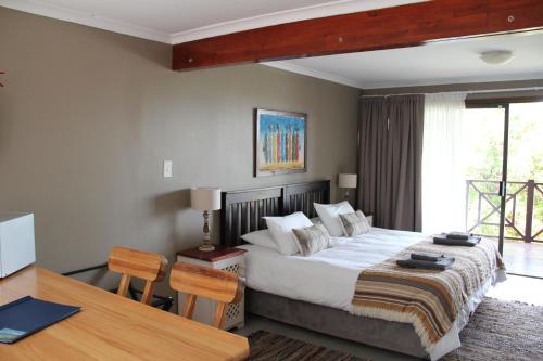 a bedroom with a bed and a table and a desk at Horizon Cottages in Noordhoek