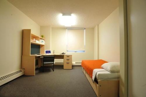 a bedroom with a bed and a desk with a computer at University of Alberta - Accommodation in Edmonton