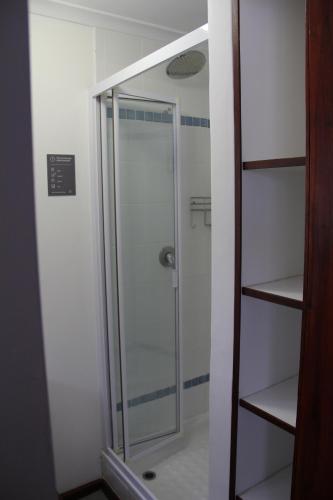 a shower with a glass door in a bathroom at Horizon Cottages in Noordhoek