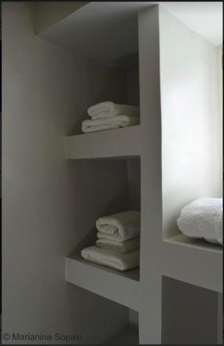 a bathroom with white towels on shelves at Spitaki Serifos Studio in Rámos