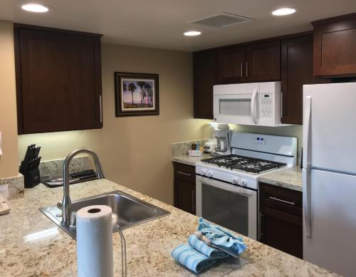 a kitchen with a sink and a white refrigerator at The Oasis Resort in Palm Springs