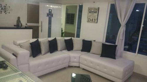 a living room with a white couch with black pillows at Sashii Hostel & Boutique. in Ríohacha