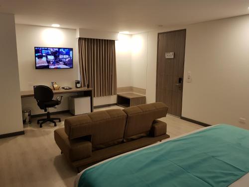 a bedroom with a couch and a desk and a tv at Hotel Nivari Duitama in Duitama