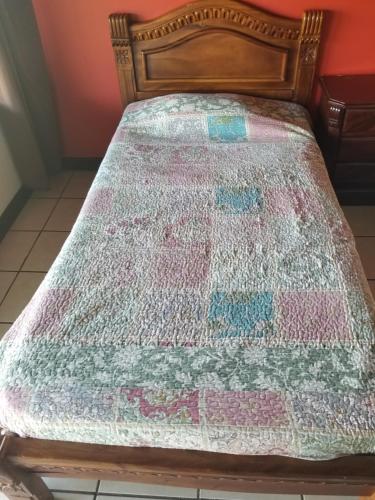 a bed with a colorful quilt on it at Hotel Monte Campana Heredia in Birrí
