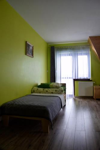 a green bedroom with a bed and a window at Apartamenty u Klisia in Ząb