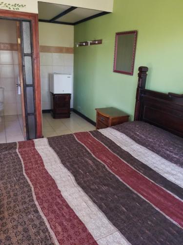 a bedroom with a large bed and a bathroom at Hotel Monte Campana Heredia in Birrí