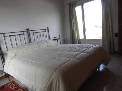 - un lit blanc dans une chambre avec fenêtre dans l'établissement Departamentos R y R Italia, à Tandil