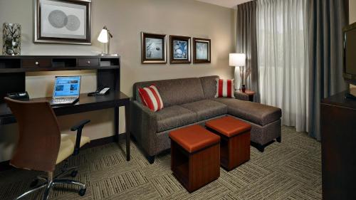 a hotel room with a couch and a desk with a laptop at Staybridge Suites Houston East - Baytown by IHG in Baytown