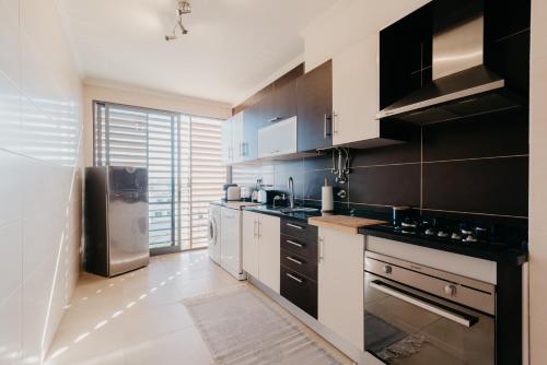 a kitchen with black and white cabinets and a refrigerator at Casa da Avenida in Olhão