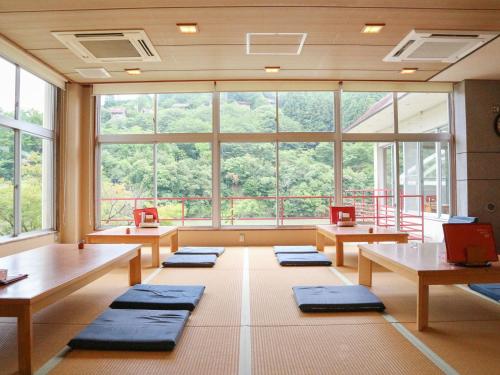a large room with tables and benches and windows at momijigawa onsen in Naka