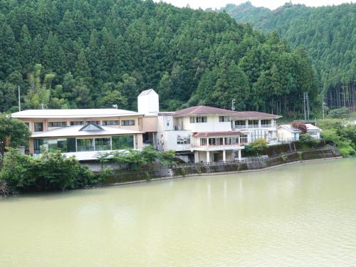 a large house sitting on the side of a river at momijigawa onsen in Naka