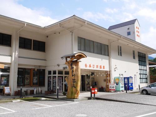 a shopping center with a large building with a large tree at momijigawa onsen in Naka
