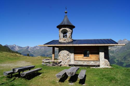 a small chapel on a hill with benches in front at Kathrin Apartments - Kapplerhof in Kappl