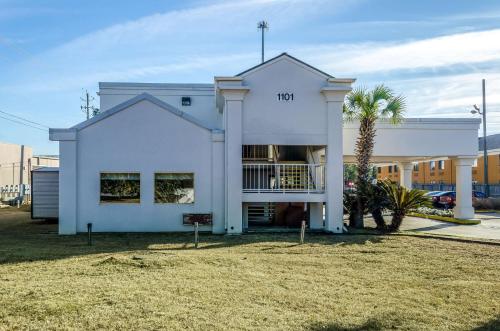 a white house with a palm tree in front of it at Motel 6-Saraland, AL in Saraland