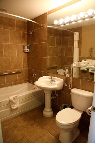 a bathroom with a sink and a toilet and a tub at Lake Grassy Inn & Suites in Lake Placid