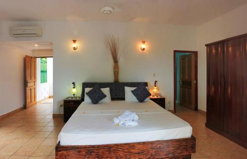 a bedroom with a large bed with white sheets at Divers Lodge Guest House in Beau Vallon