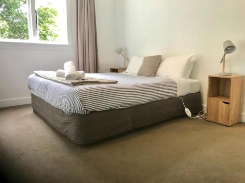 a bedroom with a large bed with white sheets and a window at Sycamore Villa, 2 bedroom apartment in Dunedin