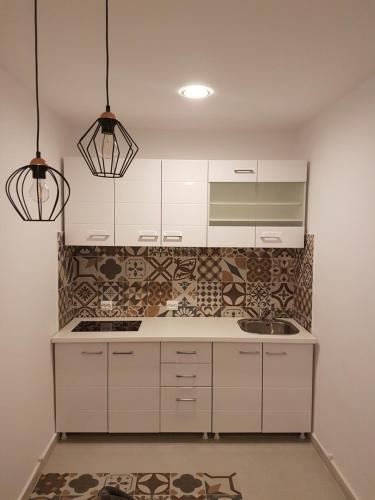 a kitchen with white cabinets and two pendant lights at Theo House in Sibiu