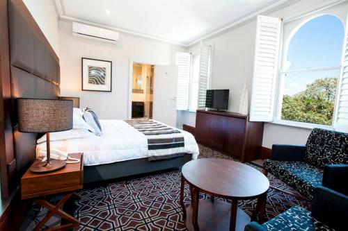 a hotel room with a bed and a table at Avonmore On The Park Boutique Hotel in Sydney
