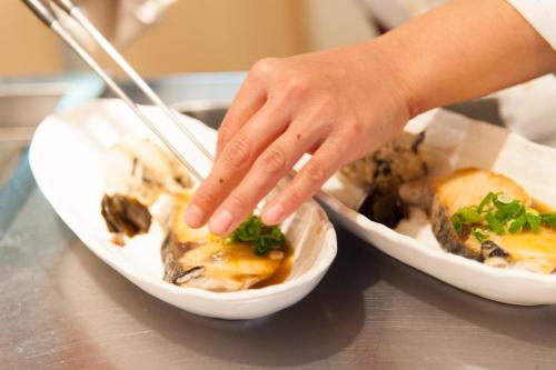 a person reaching into a bowl of food with chopsticks at Okayama View Hotel in Okayama