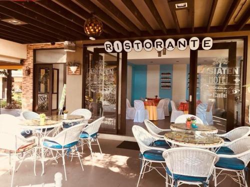 a restaurant with white chairs and tables in front of a store at Asiaten Hotel in Tarlac