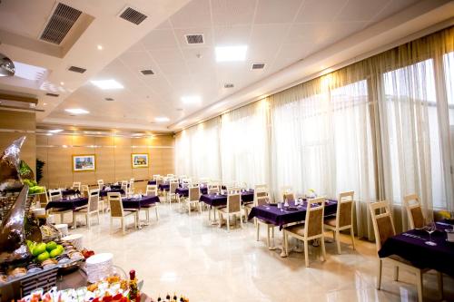 una sala da pranzo con tavoli, sedie e finestre di West Shine Hotel a Baku