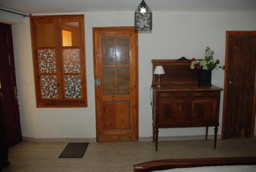 a room with a wooden door and a dresser with a lamp at Chambres d'Hôtes du Clos Semper Felix in Sainte-Bazeille