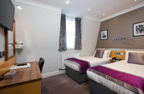 a hotel room with two beds and a desk at Best Western Victoria Palace in London