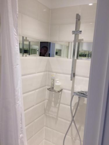 a white bathroom with a shower with a person in the mirror at Le Jardin Des Sources in La Hulpe