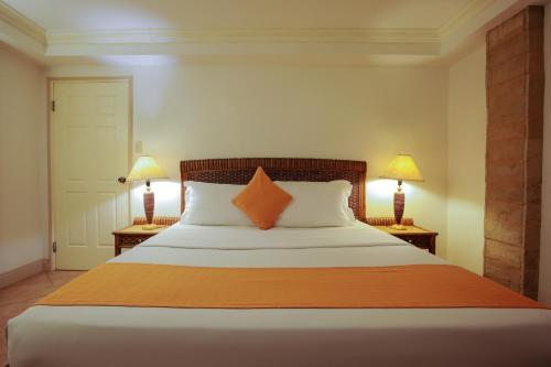 a bedroom with a large bed with two lamps at Paradise Garden Hotel and Convention Center Boracay Powered by ASTON in Boracay
