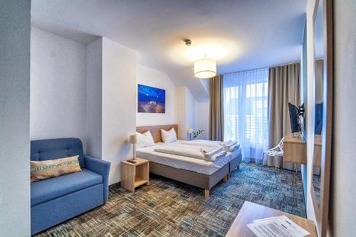 a hotel room with a bed and a blue couch at Siesta in Grzybowo
