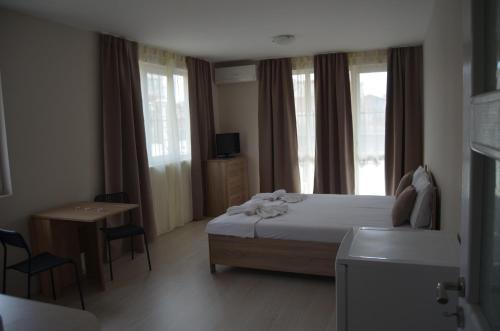 a bedroom with a bed and a table and windows at Divela 3 Apartments in Nesebar