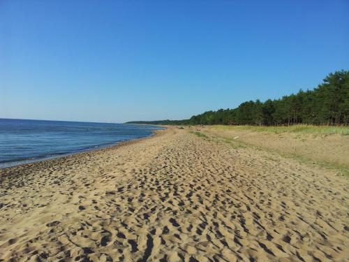 a sandy beach next to the ocean on a clear day at Apartamenti Strand in Saulkrasti