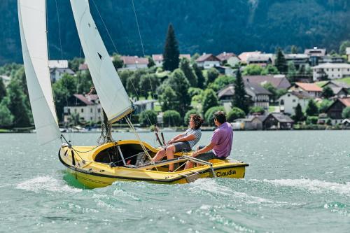 two people sitting on a yellow boat in the water at Seehotel Restaurant Lackner in Mondsee