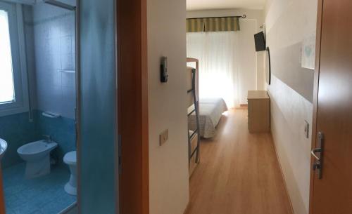 a bathroom with a toilet and a bedroom with a bed at Hotel Eden in Caorle