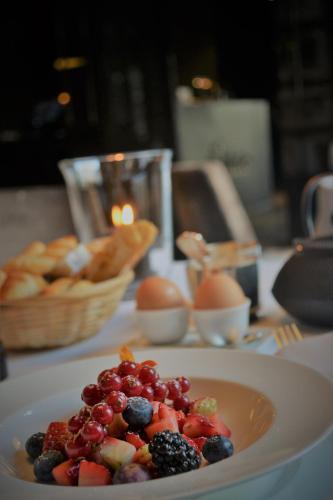 a plate of fruit on a table with eggs and bread at Hotel Odette en Ville in Brussels