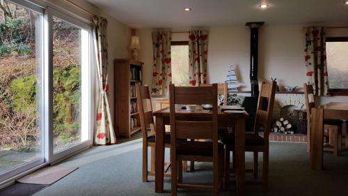 a dining room with a table and chairs and windows at The Old Cottage in Arduaine