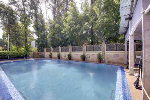 a large swimming pool in a yard with a fence at Pride Hotel Pune in Pune