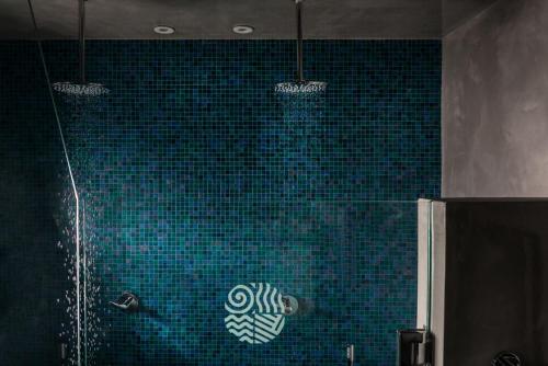a bathroom with a green tiled wall with a shower at Elements of Caldera Suites in Akrotiri