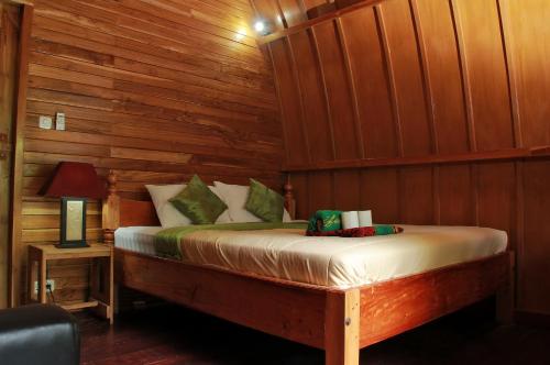a bedroom with a bed in a wooden wall at Banana Leaf Bungalow in Gili Trawangan