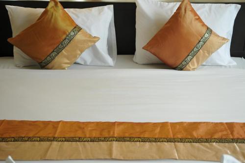 a bed with four pillows on top of it at Regent Suvarnabhumi Hotel in Lat Krabang