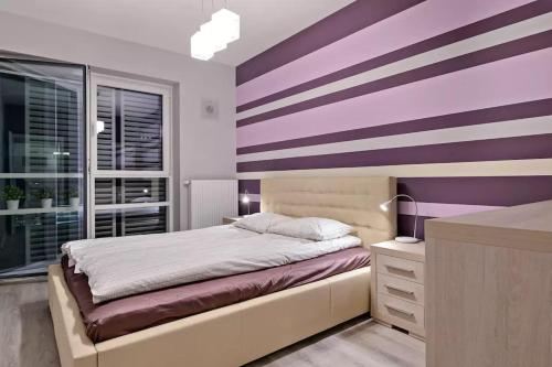 a bedroom with purple and white stripes on the wall at Strict center Towarowa in Poznań