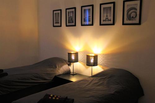 a bedroom with two beds and two lights on the wall at Appartement la Fontaine in Spa