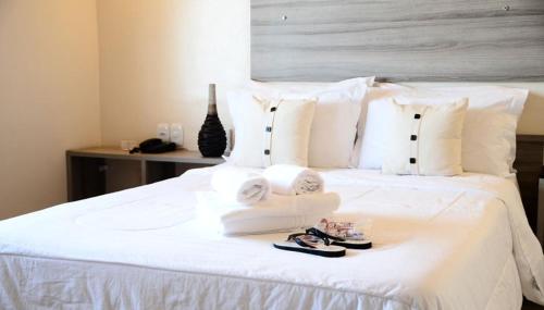 uma cama branca com toalhas e chinelos em Hotel Do Forte em Macapá