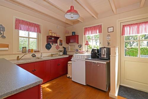 a kitchen with red cabinets and a white stove top oven at Guesthouse De Bongerd Overberg, The Orchard in Overberg