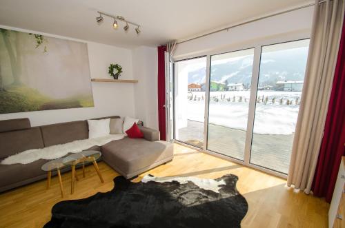 salon z kanapą i dużym oknem w obiekcie Finest Kitzblick Golf Suites by All in One Apartments w mieście Zell am See