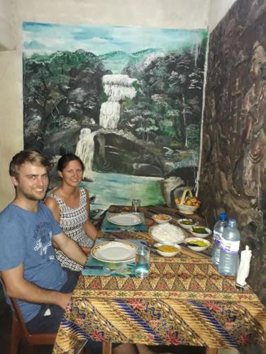 a man and woman sitting at a table with food at Sigiri Aliya Tree house in Sigiriya